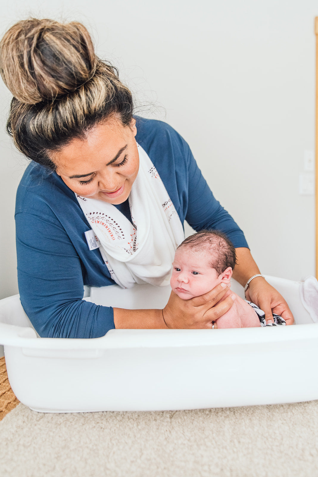 Woman bathing a newborn sitting in the tub