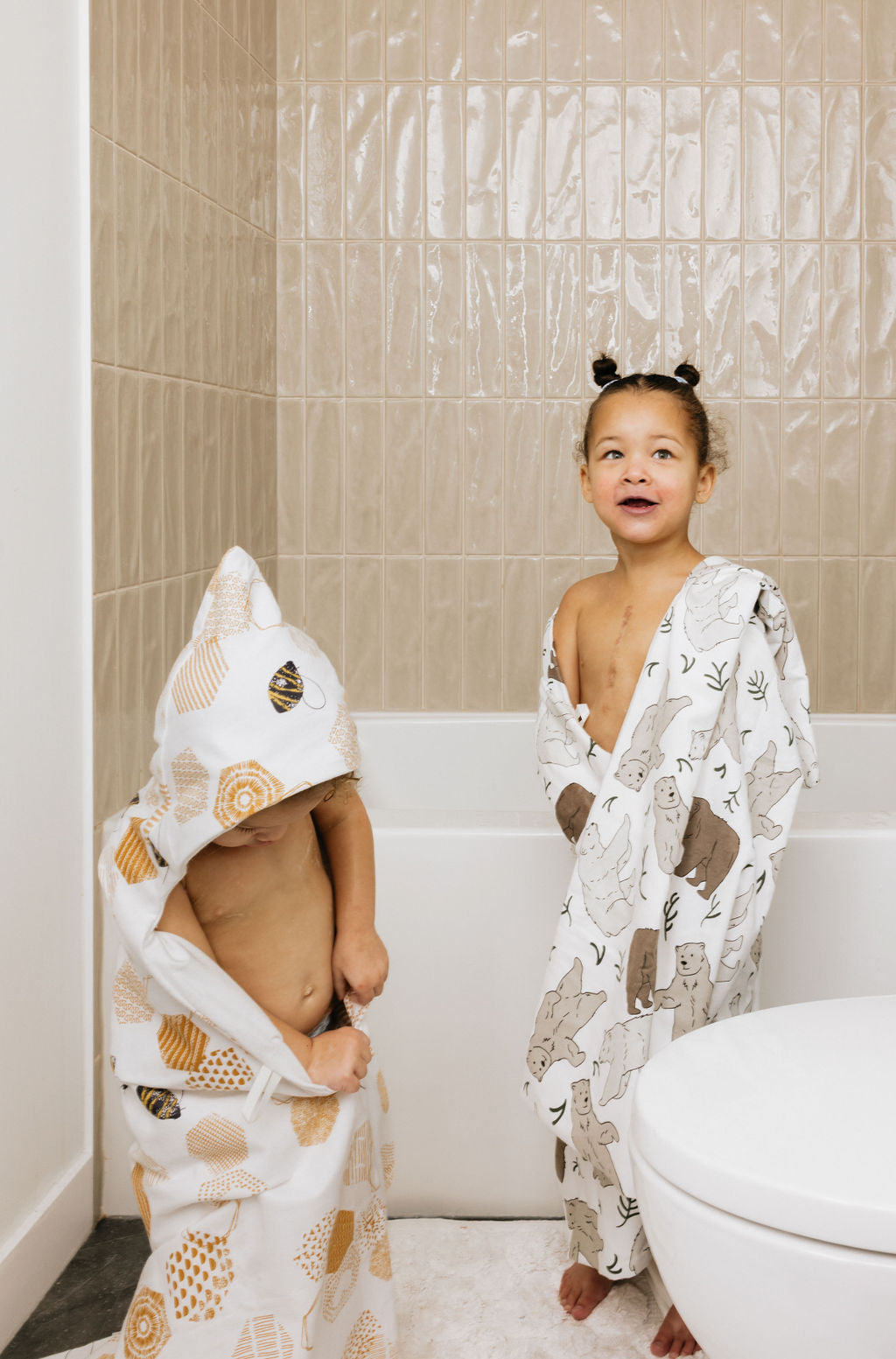 Two children wrapped in hooded towels in the bathroom